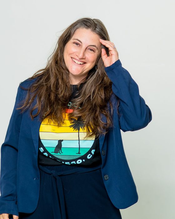Laura Lorber, J.D., laughing, in a navy blazer and San Diego T-shirt