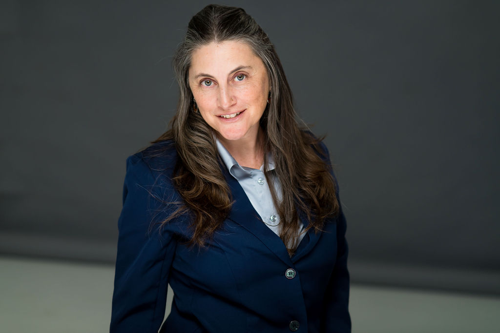 Laura Lorber in a navy blazer against a gray studio background